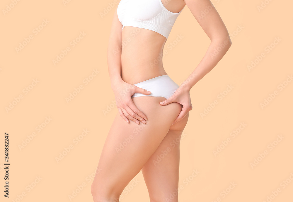 Beautiful young woman in underwear on color background. Concept of cellulite