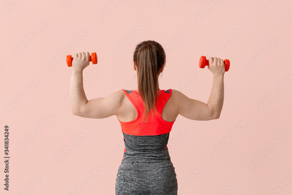 Sporty muscular woman with dumbbells on color background