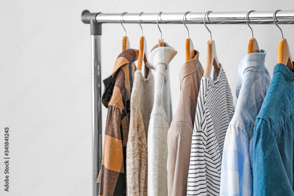 Rack with clothes on light background