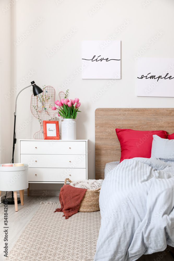 Interior of beautiful modern bedroom with spring flowers