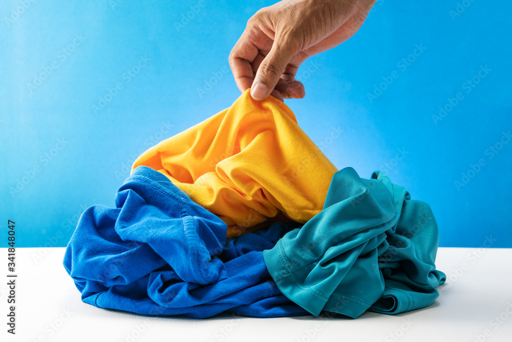 Hand holding dirty laundry on white table Blue background.