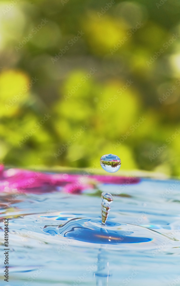 Closeup of clean water drops falling on water, green nature background, water wave texture