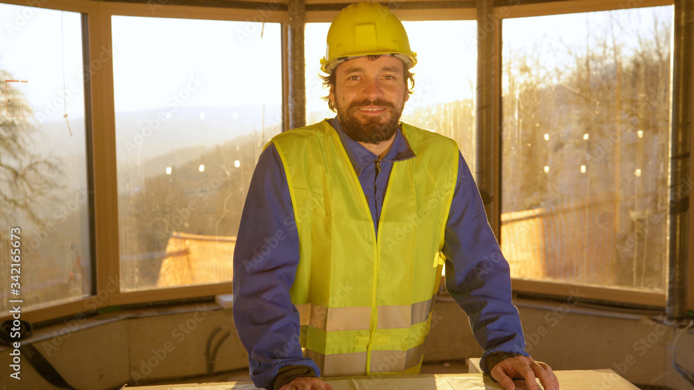 PORTRAIT: Happy contractor smiles after analysing floor plans on a sunny morning