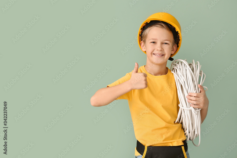 Cute little electrician showing thumb-up on color background