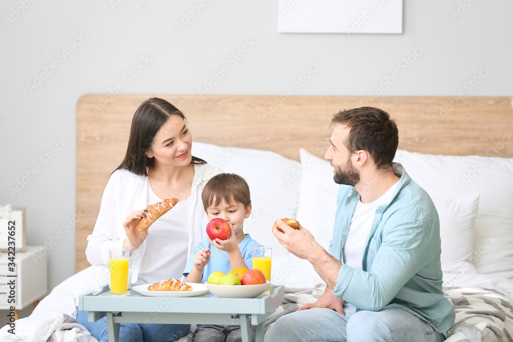 Happy family having breakfast in bedroom