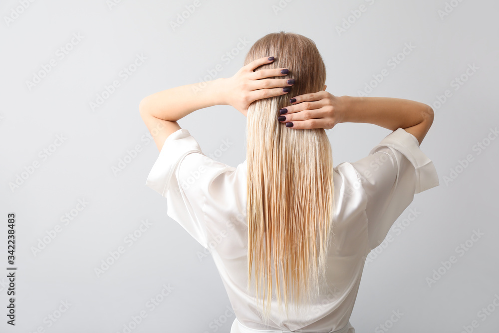 Beautiful young woman with healthy hair on grey background