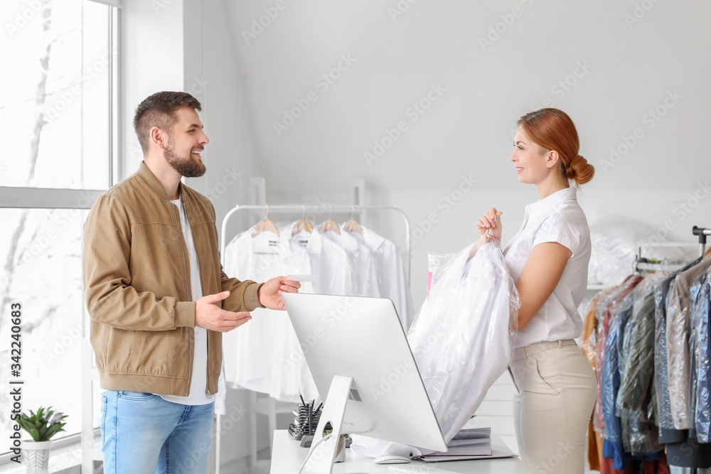 Client taking clothes from modern dry-cleaners