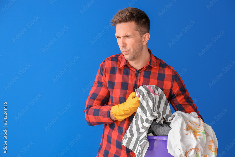 Displeased man with dirty clothes on color background