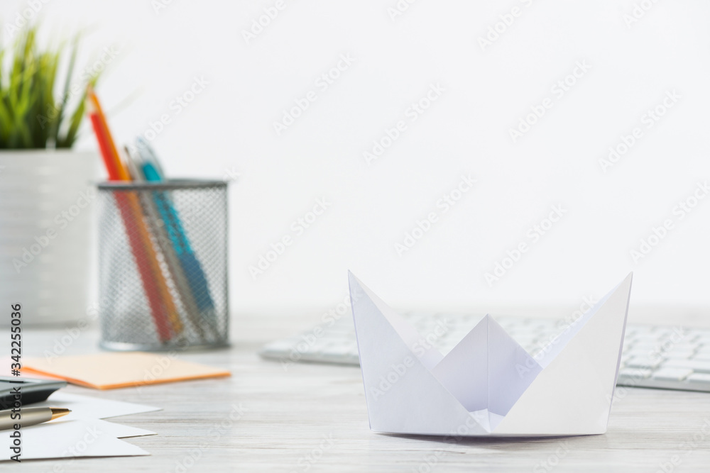 Wooden office desk with white origami boat.