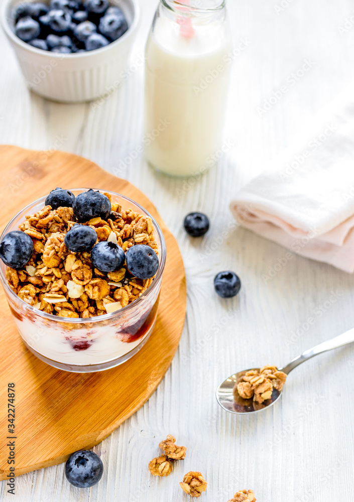 Fitness breakfast with granola, milk and berries on white background