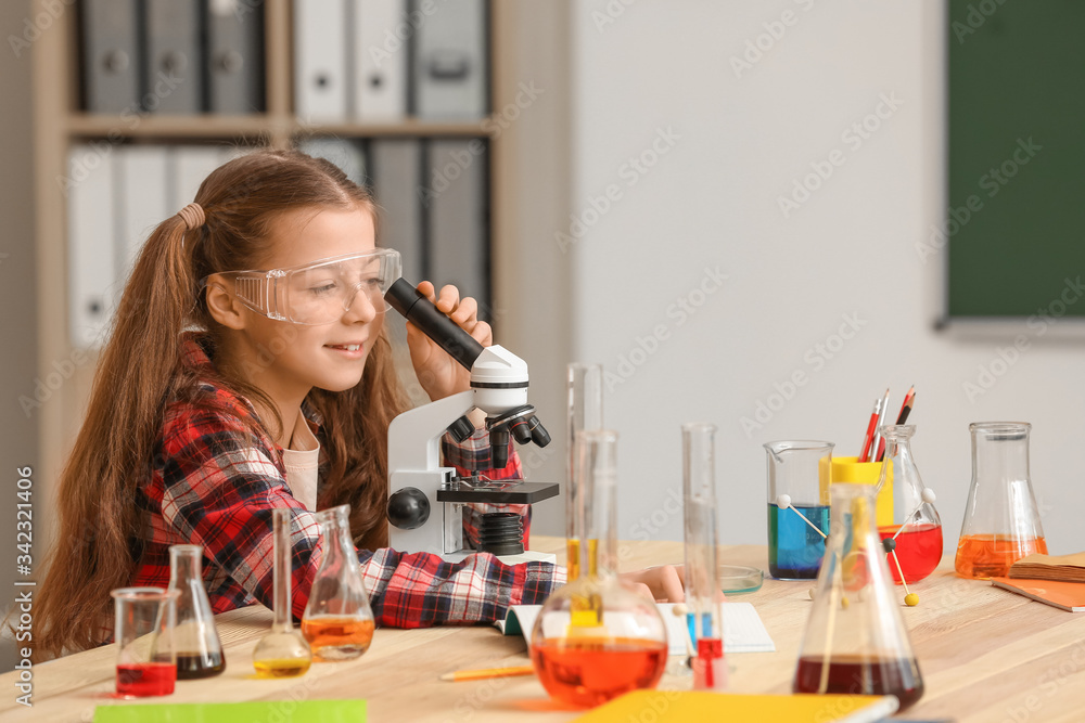 Cute little girl at chemistry lesson in classroom