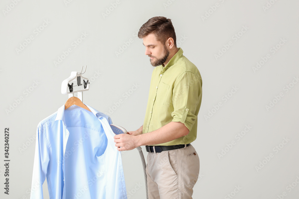 Worker of modern dry-cleaners on light background