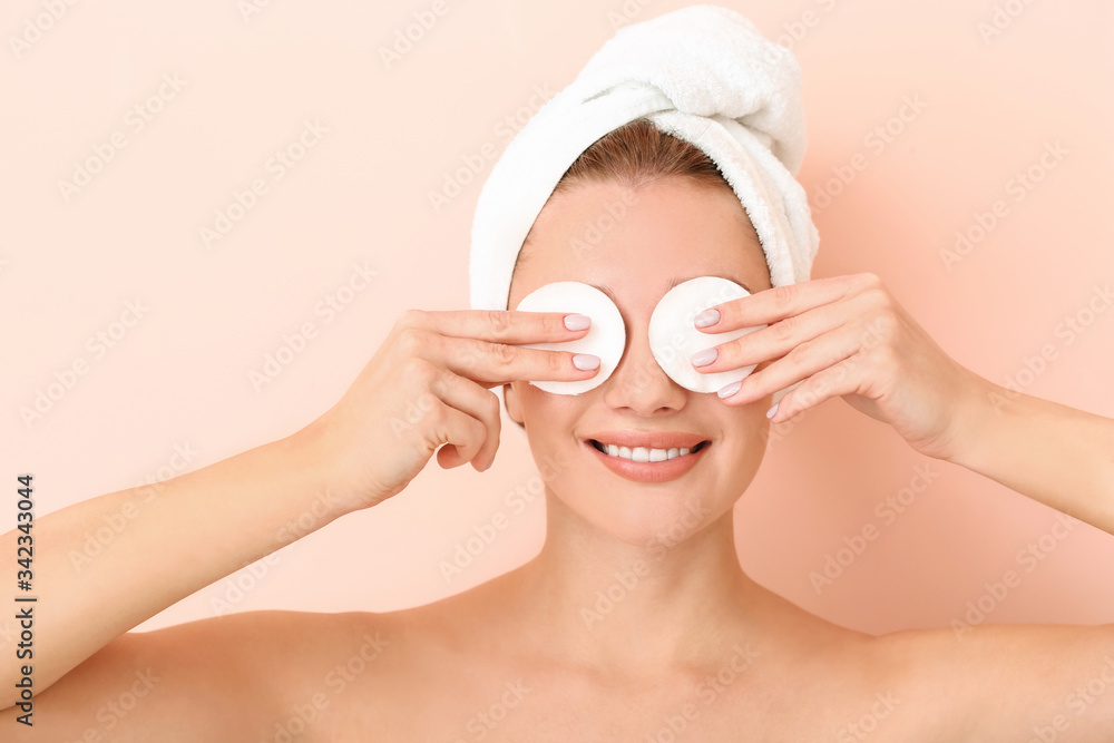 Beautiful young woman with cotton pads on color background