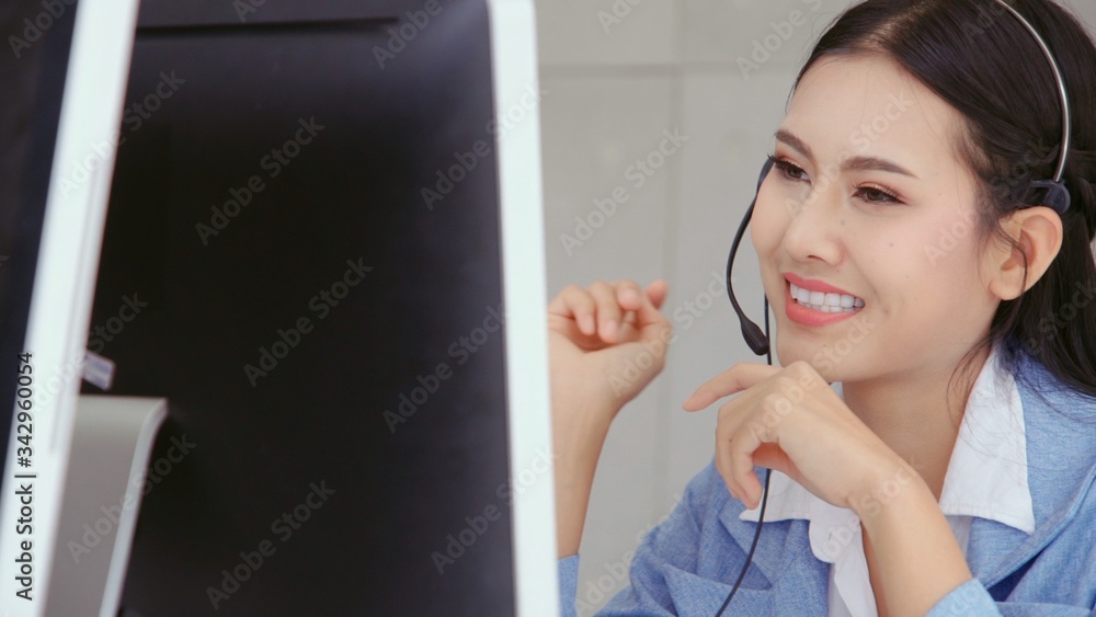 Customer support agent or call center with headset works on desktop computer while supporting the cu