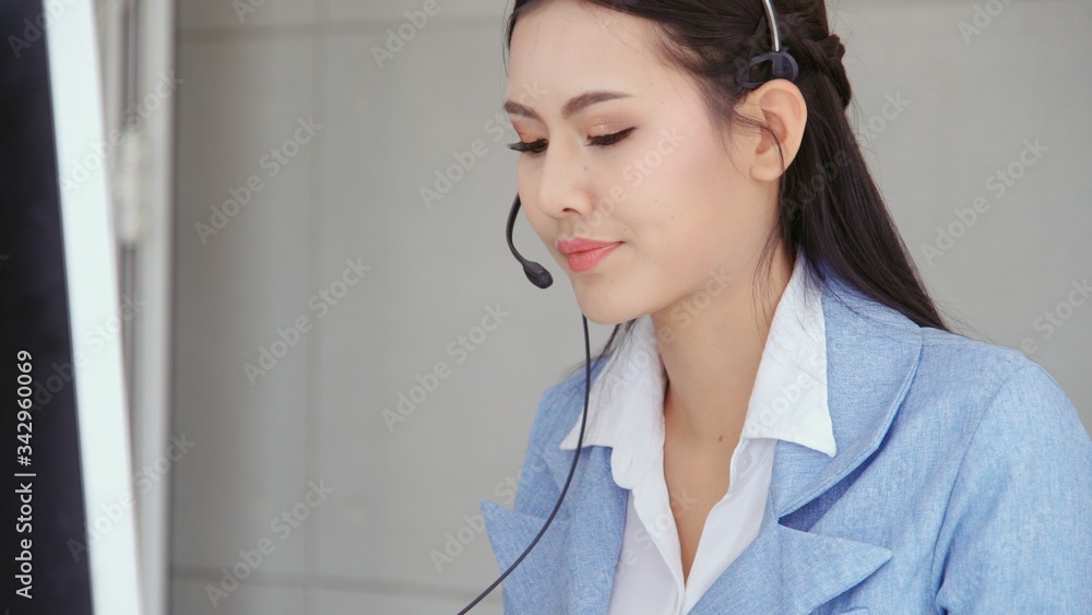 Customer support agent or call center with headset works on desktop computer while supporting the cu