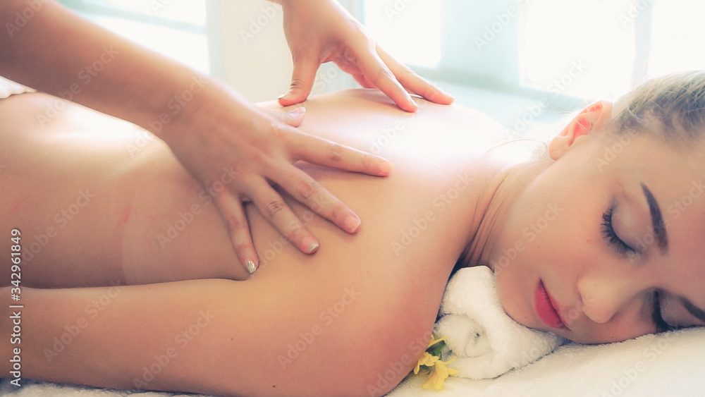 Relaxed woman getting back massage in luxury spa with professional massage therapist. Wellness, heal