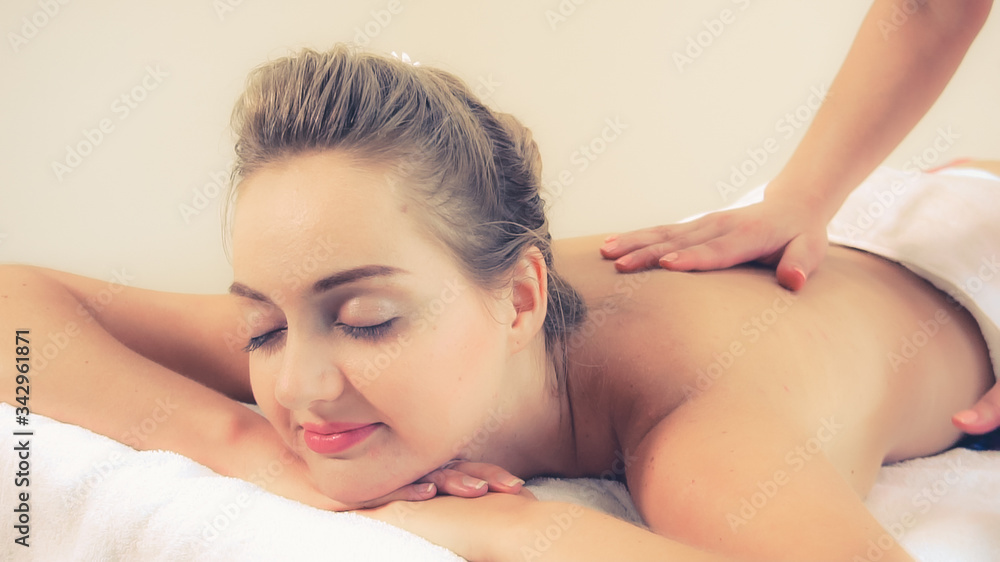 Relaxed woman getting back massage in luxury spa with professional massage therapist. Wellness, heal