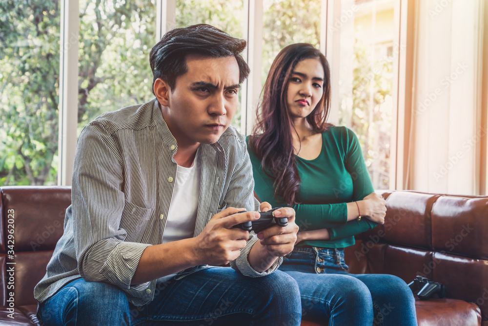 Young Asian couple suffers from computer games addiction. Family problem concept.