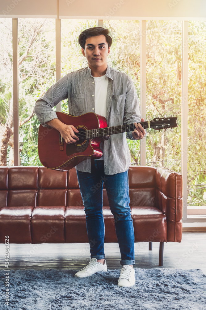 Young guitar player holding his guitar at home. Music and song concept.