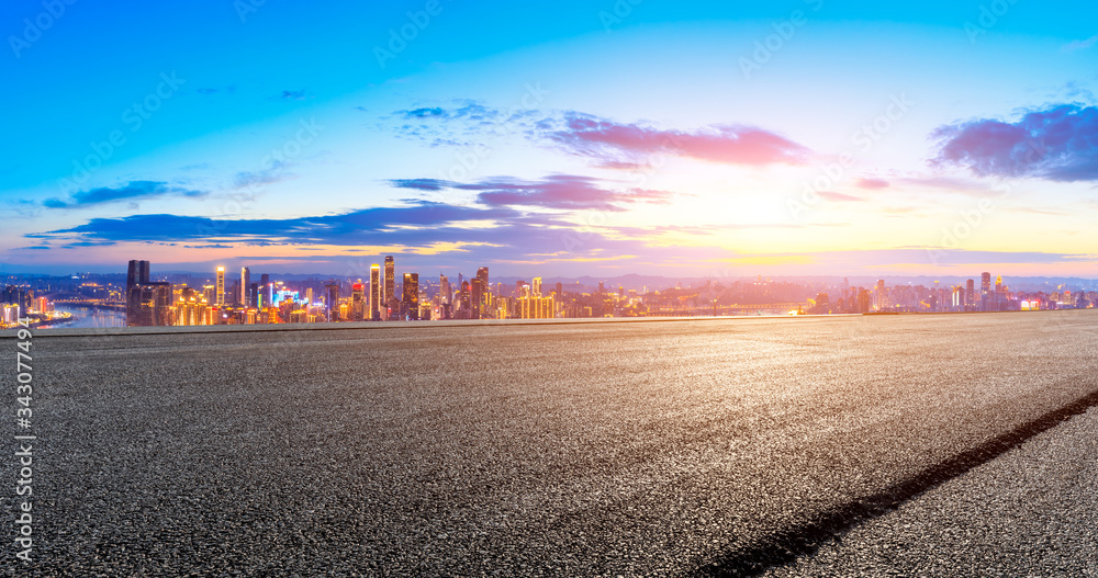 空旷的柏油路，日落时的重庆城市天际线和建筑，中国。