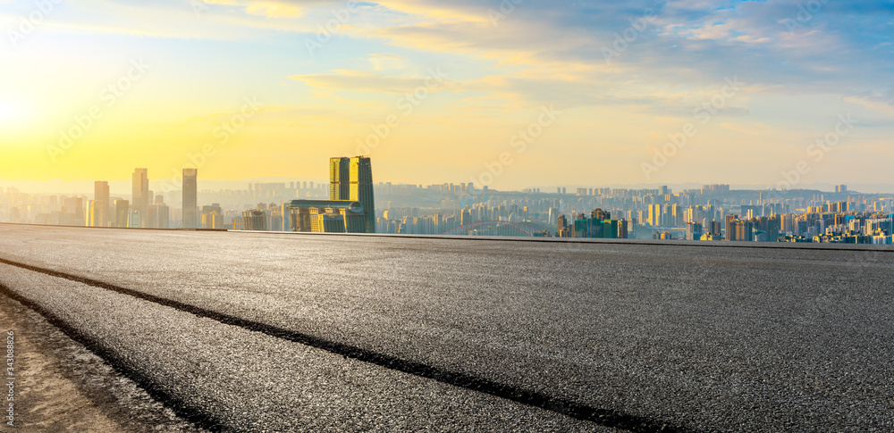 空旷的柏油路，日落时的重庆城市天际线和建筑，中国。