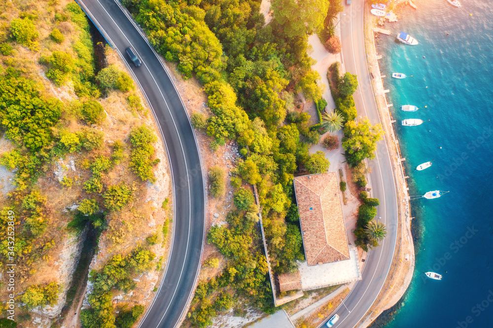 鸟瞰道路，水中的船只和游艇，夏天日落时的建筑。五颜六色的景观wi