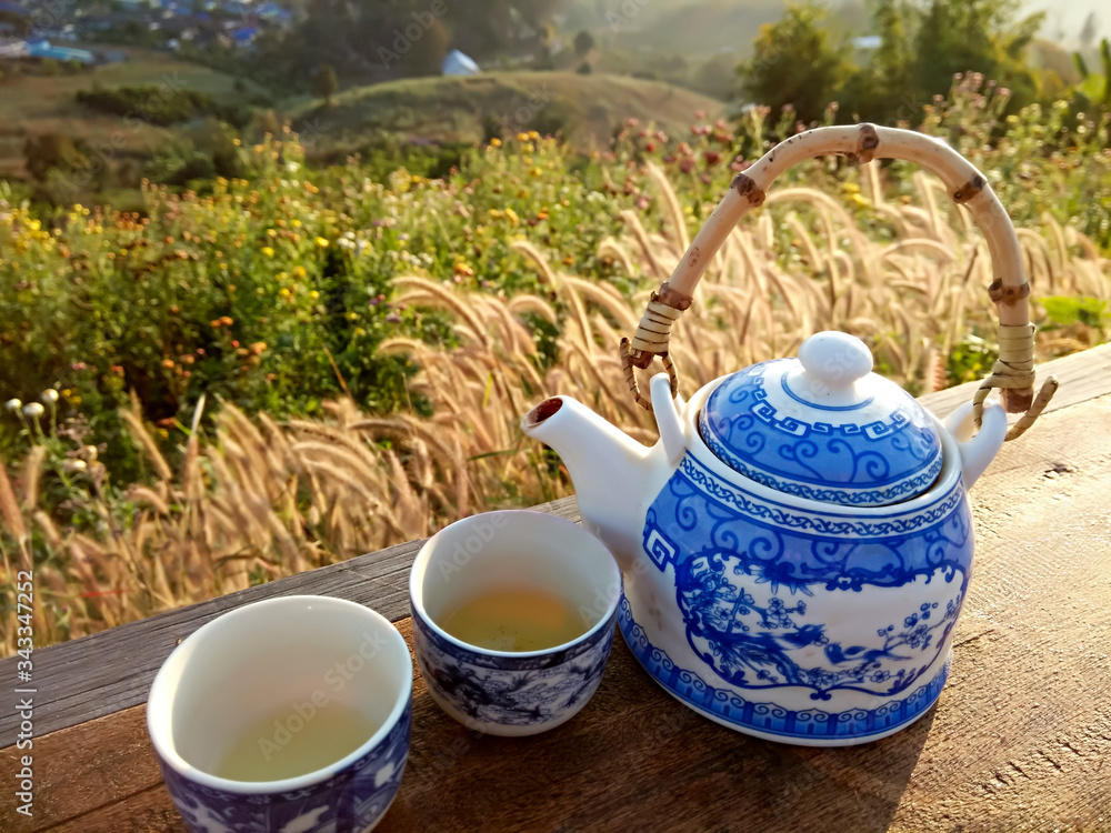 A teapot placed on a wooden table in the morning light against a blurred background