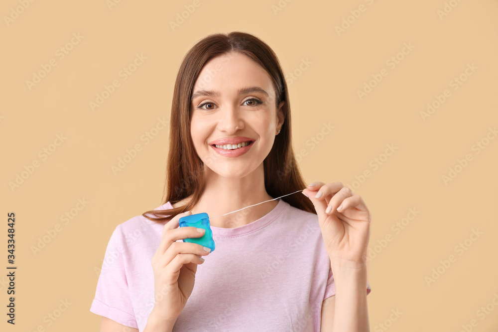 Young woman with beautiful smile and floss on color background