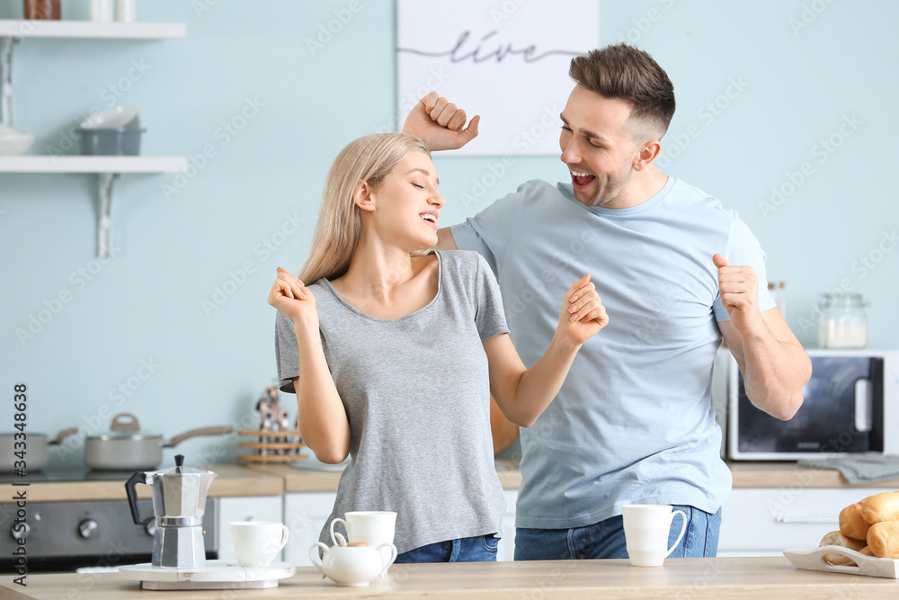 Happy dancing young couple in kitchen