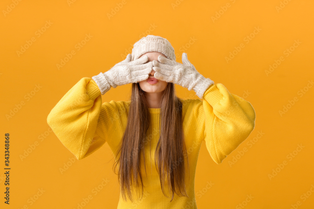 Beautiful young woman in warm sweater on color background