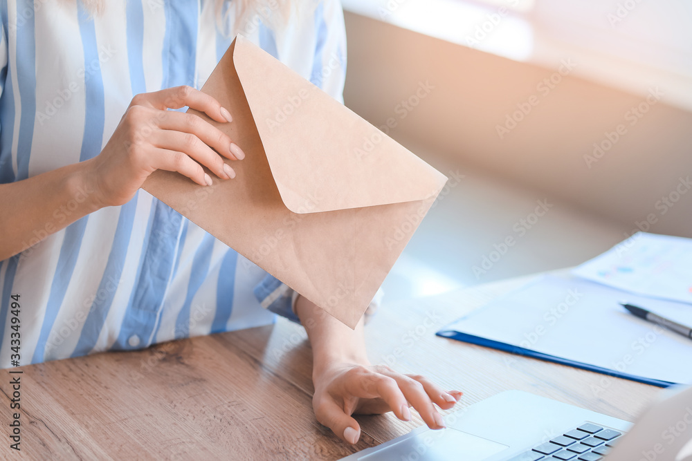 Young woman with laptop and letters in office