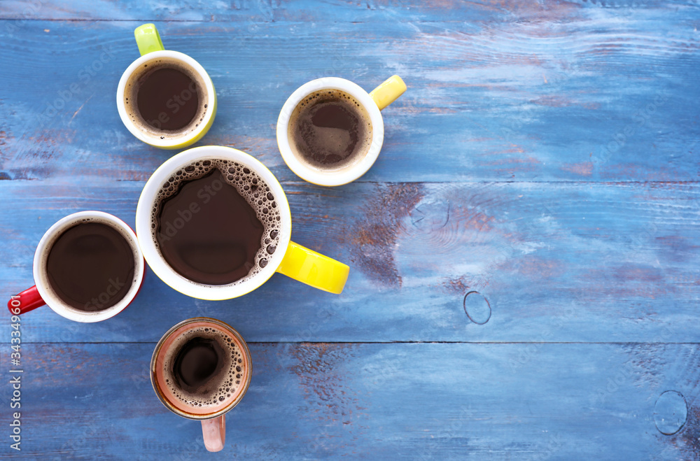 Cups of coffee on color wooden background