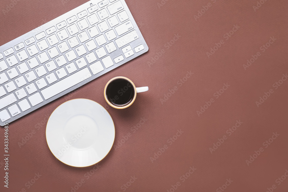 Cup of coffee with computer keyboard on color background