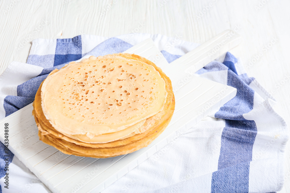 Board with tasty blini on table