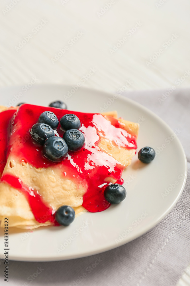 Plate with tasty blini and berries on table, closeup