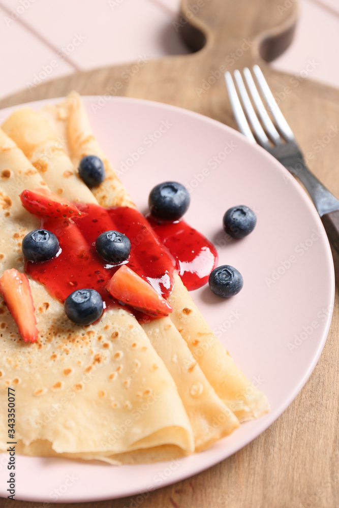 Plate with tasty blini and berries on table, closeup