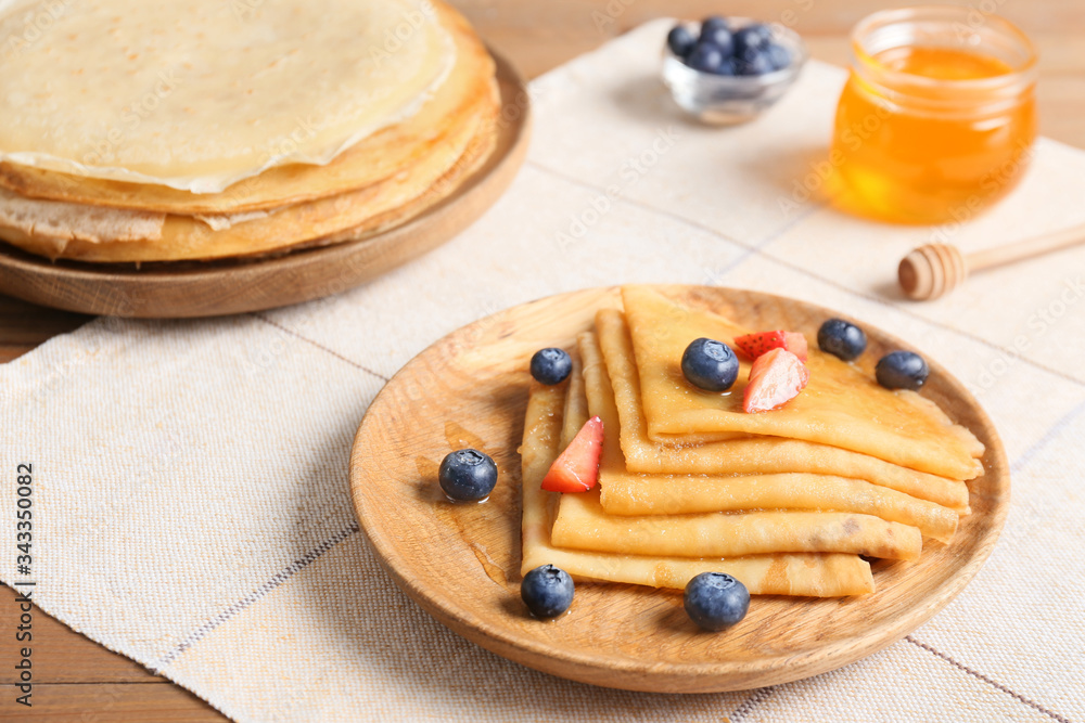 Tasty blini with berries on table