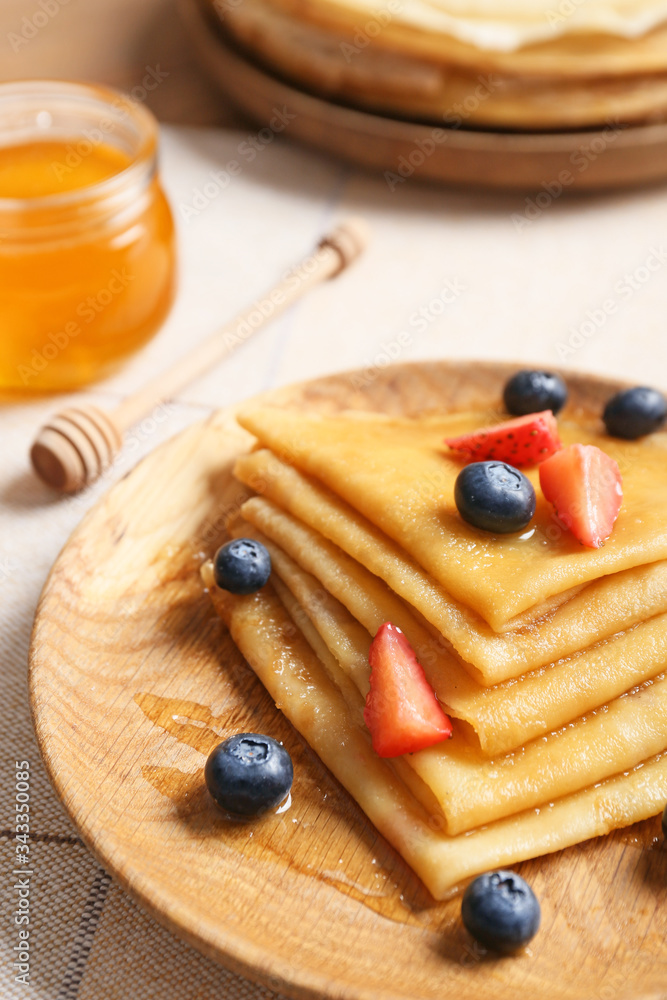 Plate with tasty blini and berries on table, closeup