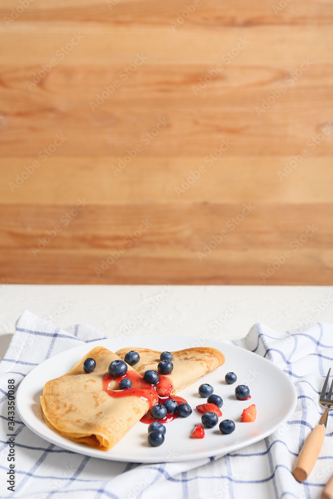 Tasty blini with berries on table