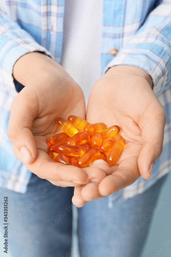 Woman with fish oil capsules, closeup