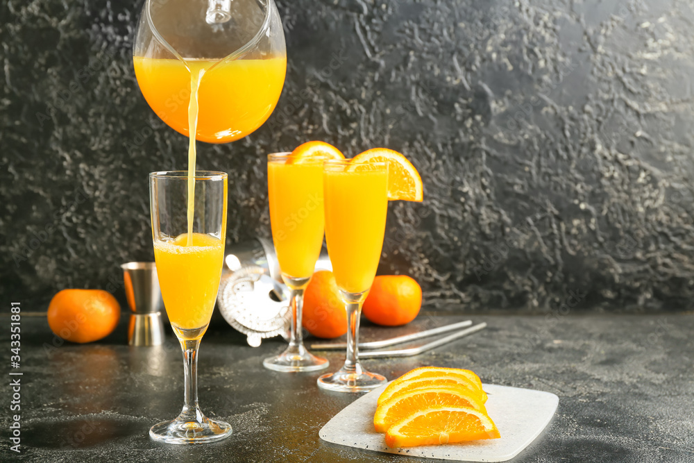 Pouring of orange juice in glass on table