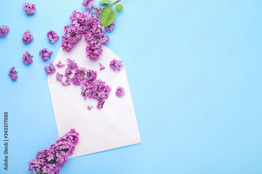 Beautiful lilac flowers and envelope on color background