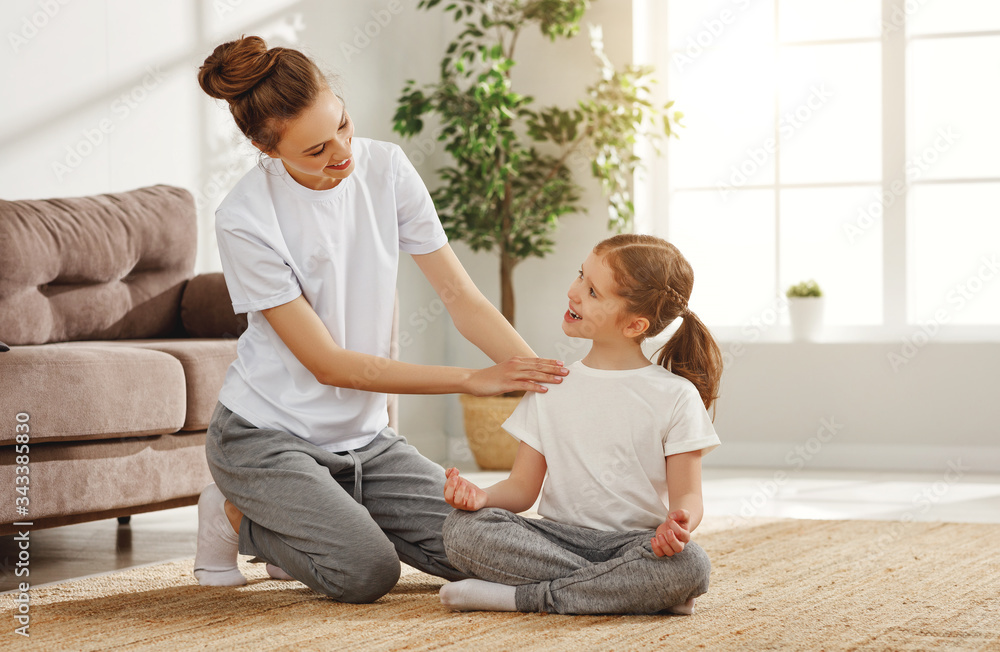 Mother teaching girl to practice yoga in living room