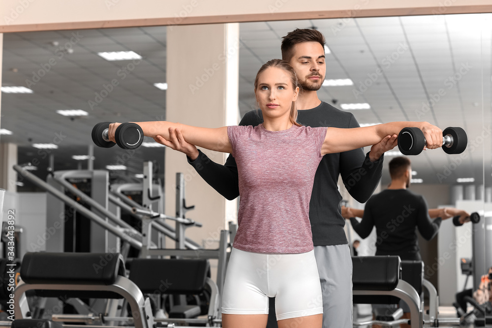 Sporty young woman training with coach in gym