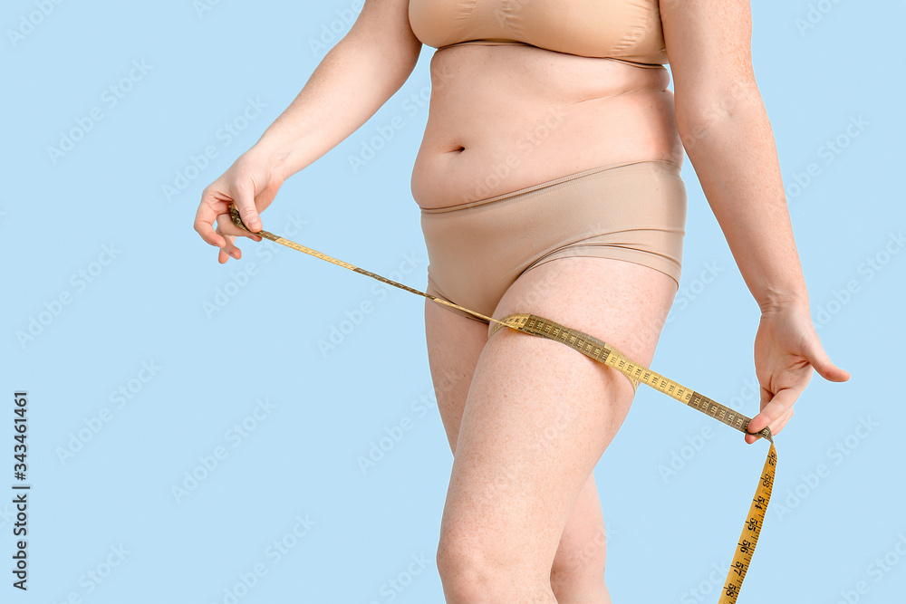 Overweight woman with measuring tape on color background. Weight loss concept