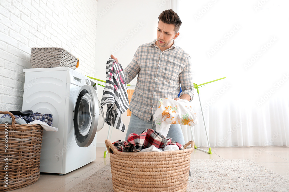 Troubled man doing laundry in bathroom