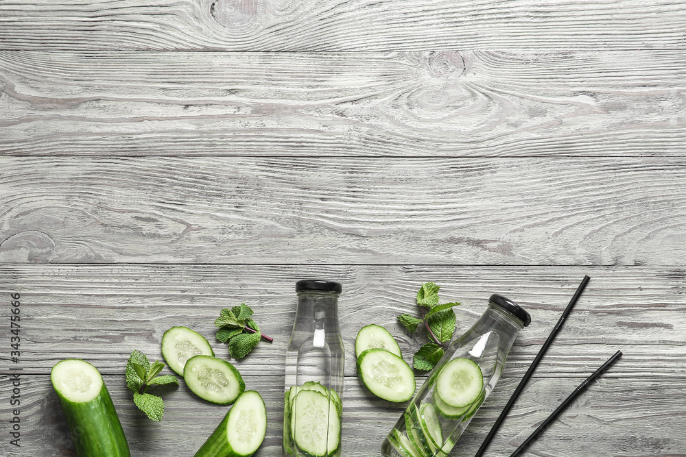 Bottles of infused cucumber water on wooden background