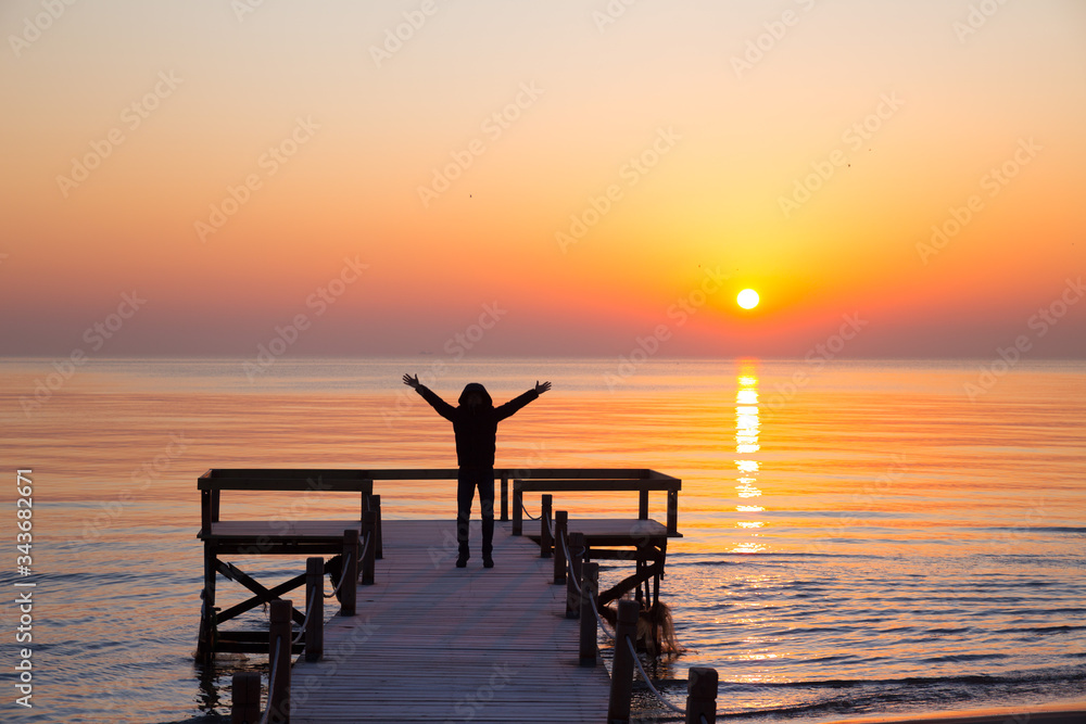 A man jumping in front of sunrise on a wooden deck