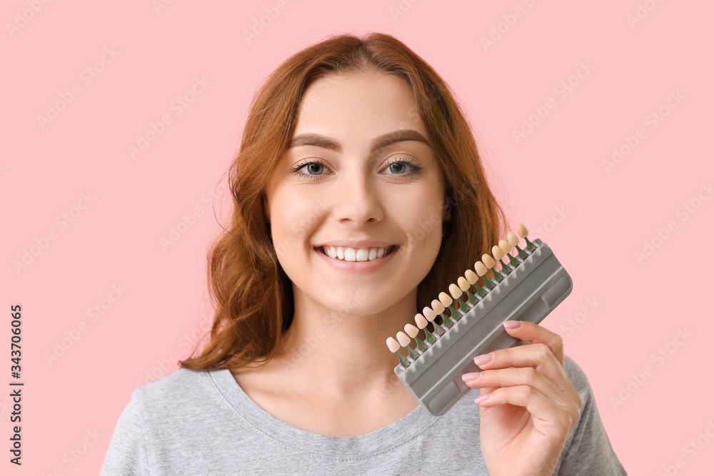 Beautiful young woman with teeth color samples on color background