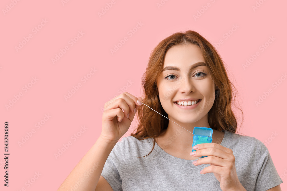 Beautiful young woman with dental floss on color background